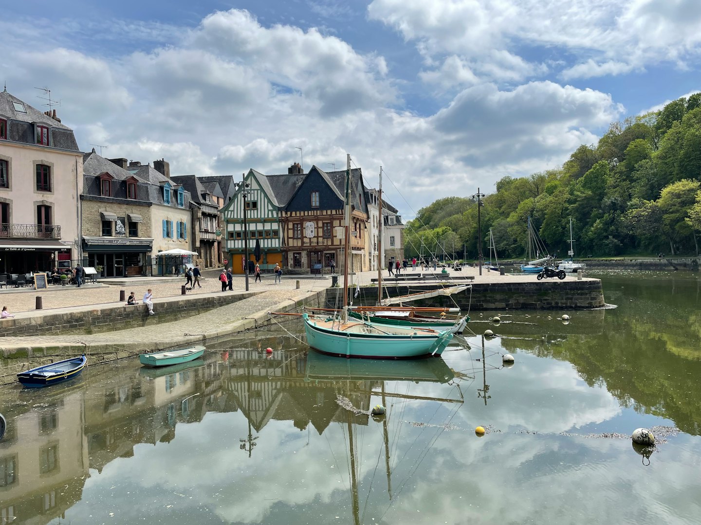 Sailboats and rowboats moored in a European harbor town with historic buildings.