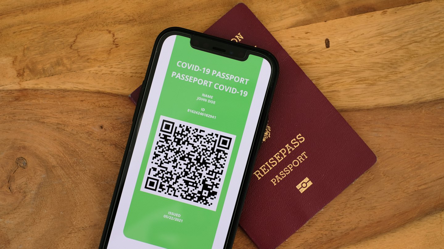 Smartphone displaying COVID-19 passport lies on physical passport.