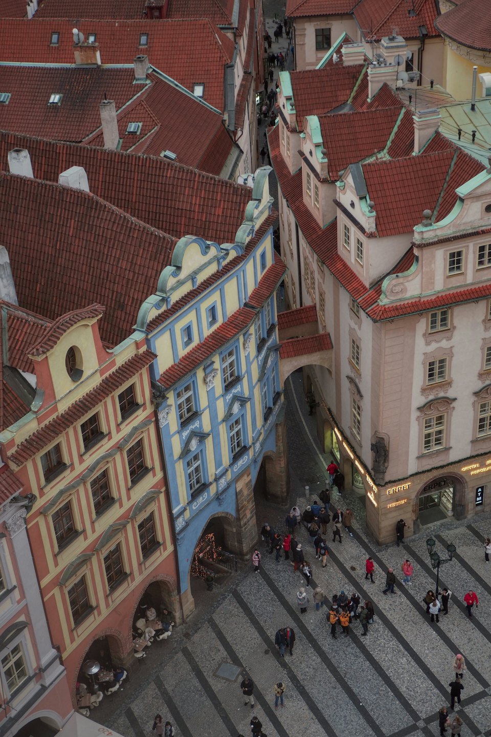 Pedestrians walk on a cobblestone street in a historic city.