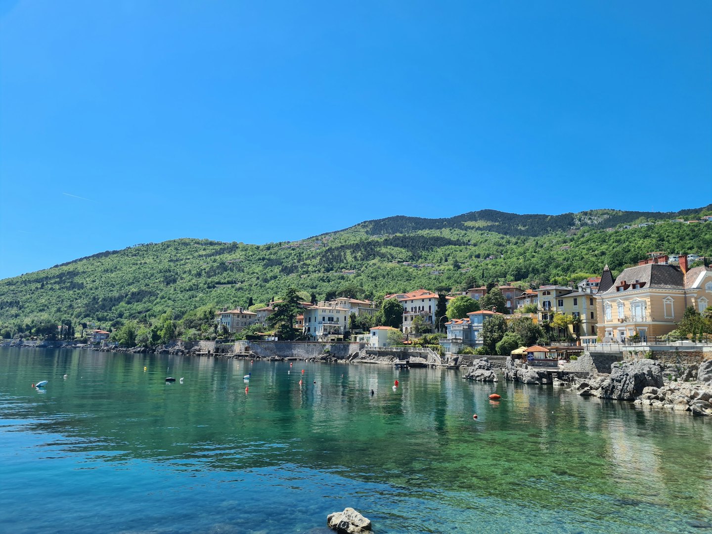 Mediterranean town with terracotta roofs along a turquoise coastline.